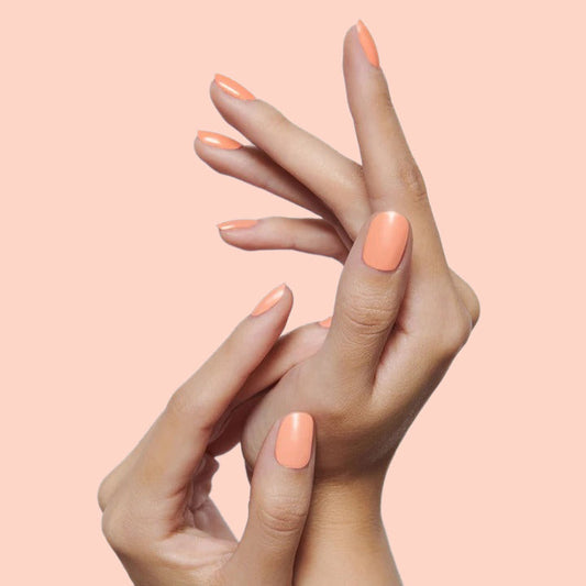 Hands with nails painted in vibrant coral shade Wild & Free for a fresh and long-lasting at-home mani