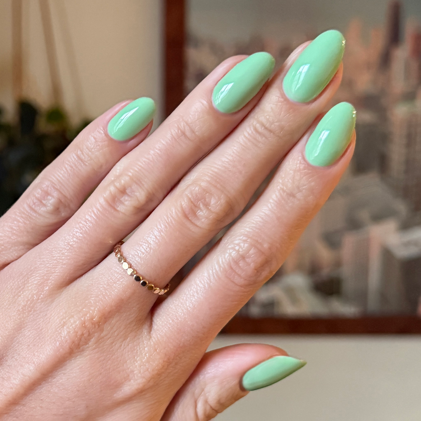 Hand with nails painted Aced It pastel green polish for a smooth, fresh, and quick-dry at-home manicure look
