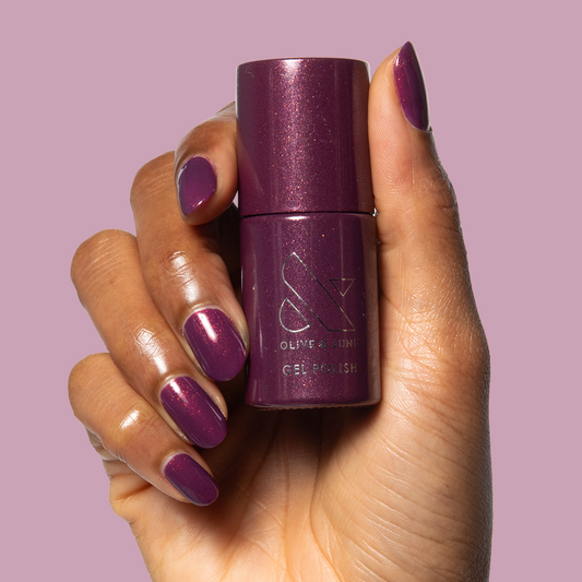 On the Promenade - Gel bottle held with matching shimmering mulberry purple gel polish on medium nails by Olive and June