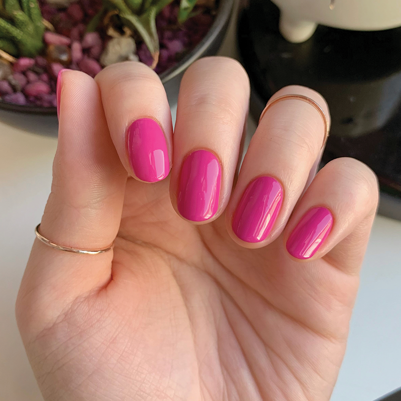 Hand with smooth, glossy WILD ORCHID nail polish in bright magenta purple showing a neat manicure with gold rings