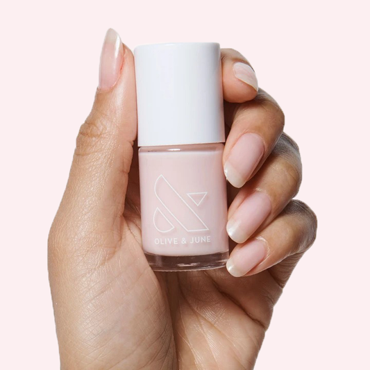 Hand holding a bottle of CCT sheer neutral pastel pink polish with natural nails for a soft manicure look