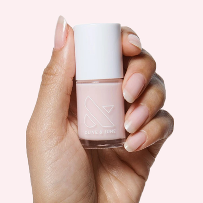 Hand holding Soap Nails Long-Lasting Mani System bottle with soft neutral pink polish for at-home manicure