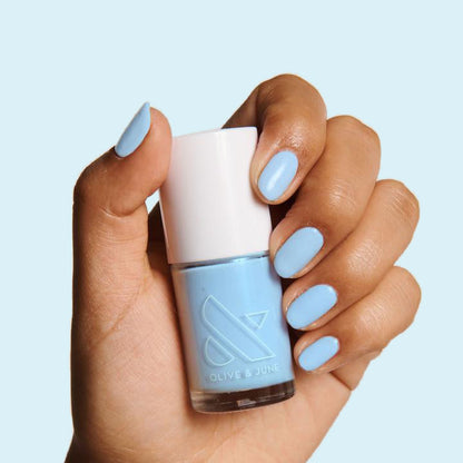 Hand holding Honest & True nail polish with nails painted in serene blue for a calm and long-lasting mani