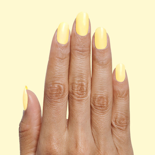Hand with nails painted in Bright & Focused yellow for a bright, creative at-home manicure look using gel polish