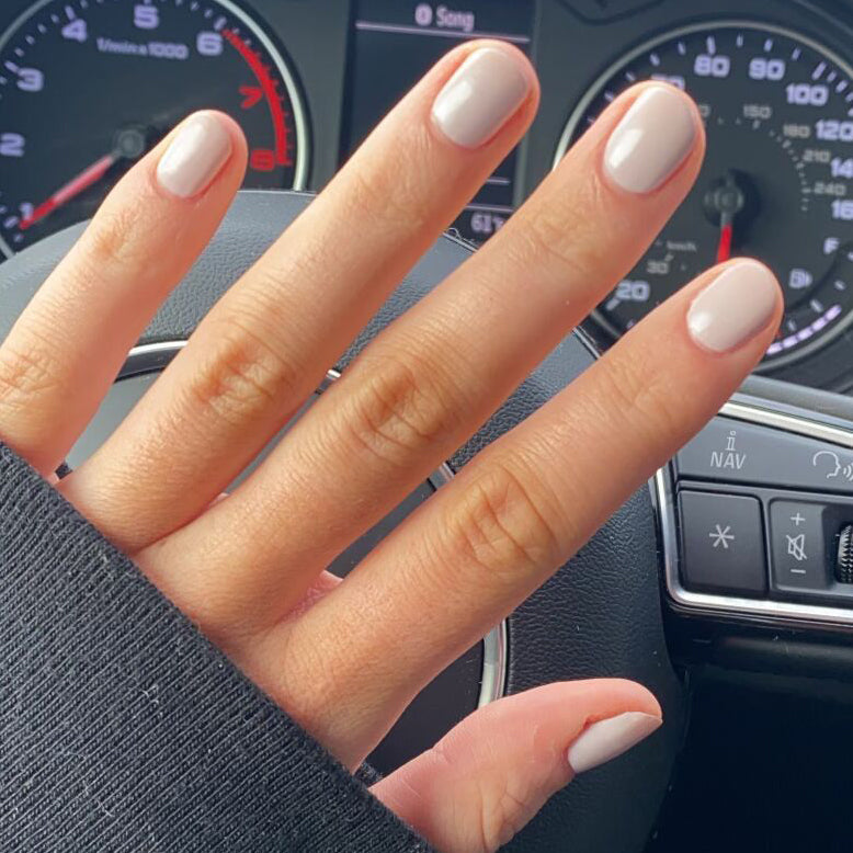 Hand with nails polished in CDJ showing a smooth, cool creamy neutral gel polish perfect for at-home manicures