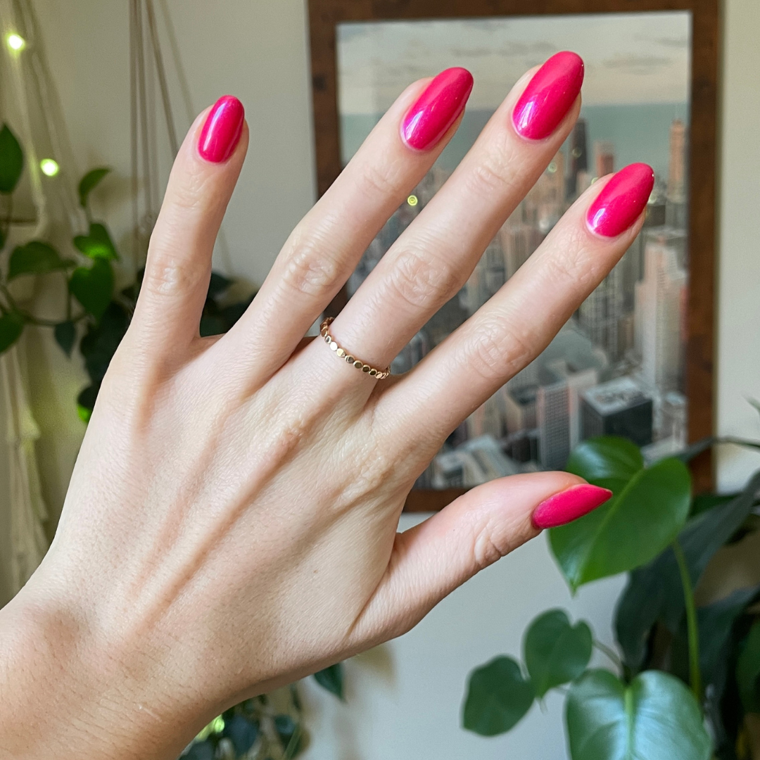 Hand with medium-length nails painted in bright berry-pink Berries gel polish showing glossy, fresh mani indoors