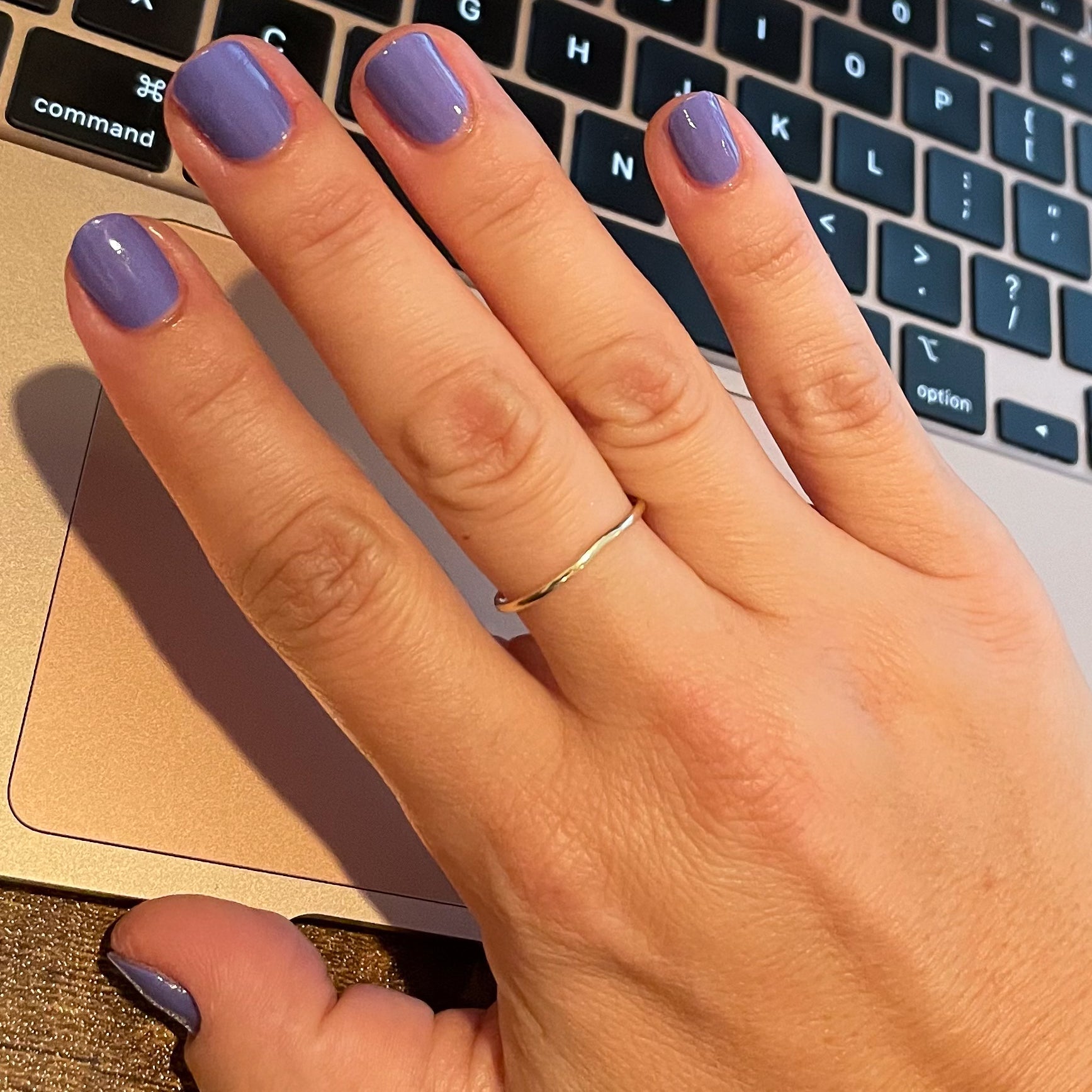 Hand with Royal polish in glossy muted purple on natural nails resting on a laptop keyboard surface