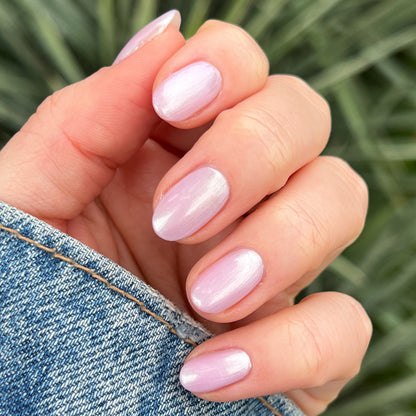 Hand with rounded nails painted in sheer iridescent Purple Puka gel polish showing a soft lavender mani