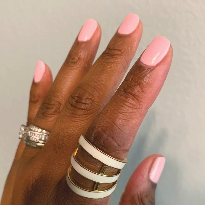 Hand with nails painted in soft pink SE polish by Olive and June, showing a smooth and polished at-home manicure look