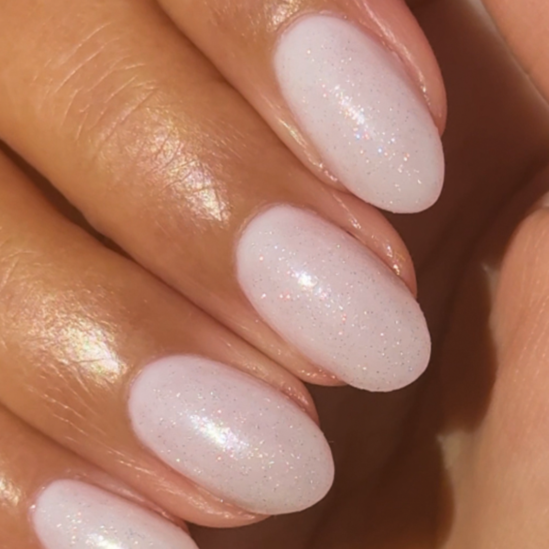 The Celestial Effect Top Coat on natural nails with a soft white base and fine shimmering micro-shimmer for a radiant mani