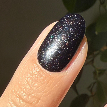 The Celestial Effect Top Coat adding a shimmering starry sparkle finish over a dark manicure on a natural nail.