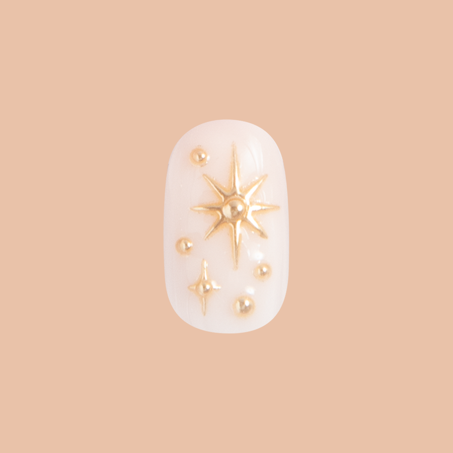 Confetti Sparkle - Press-On | Short | Round false nail with milky base and raised gold star accents for easy at-home mani