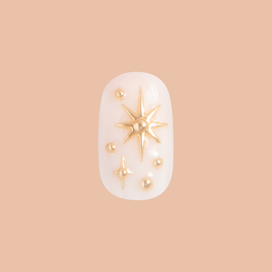 Confetti Sparkle - Press-On | Short | Round false nail with milky base and raised gold star accents for easy at-home mani