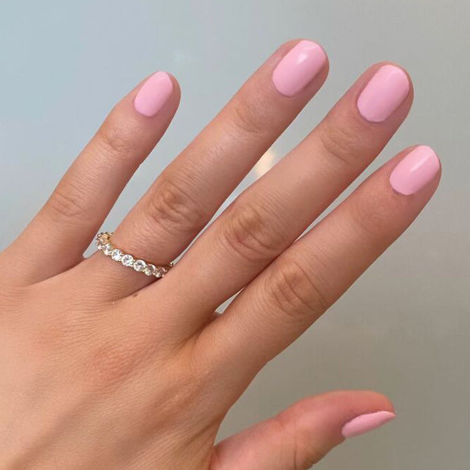 Hand with nails coated in SE polish by Olive and June, showcasing a bright and soft pink manicure perfect for summer at home