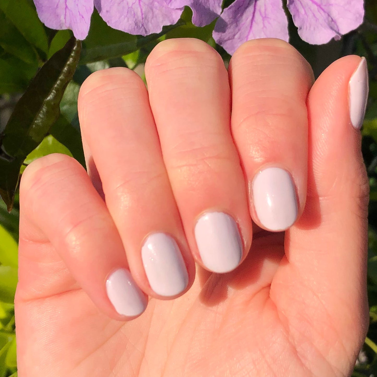 Hand displaying nails painted with TT, a soft lavender gel polish balanced with subtle grey undertones for a polished look