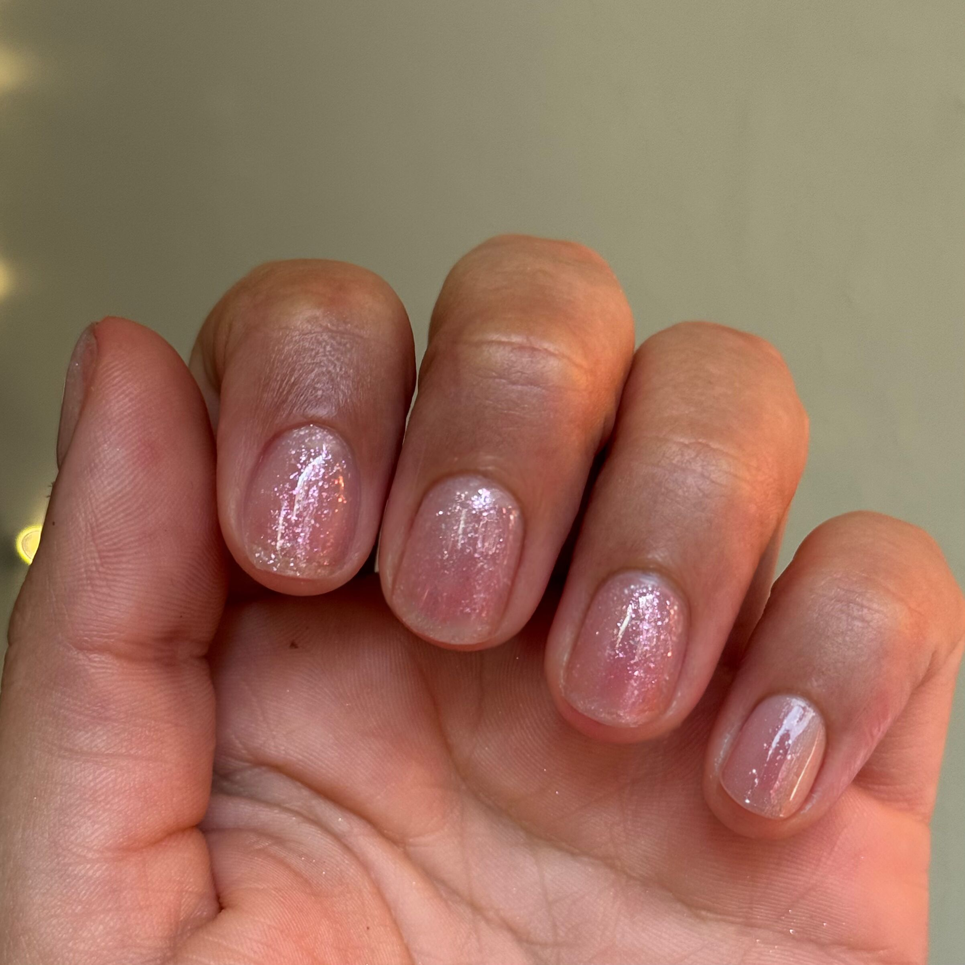 Hand with short natural nails showcasing a sparkly sheer polished with DIAMONDS ARE A MANI’S BEST FRIEND Gel for an elegant mani