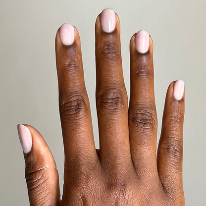 Fingers with rounded nails painted in Dream Job - Gel neutral milky sheer pink gel polish manicure against beige background