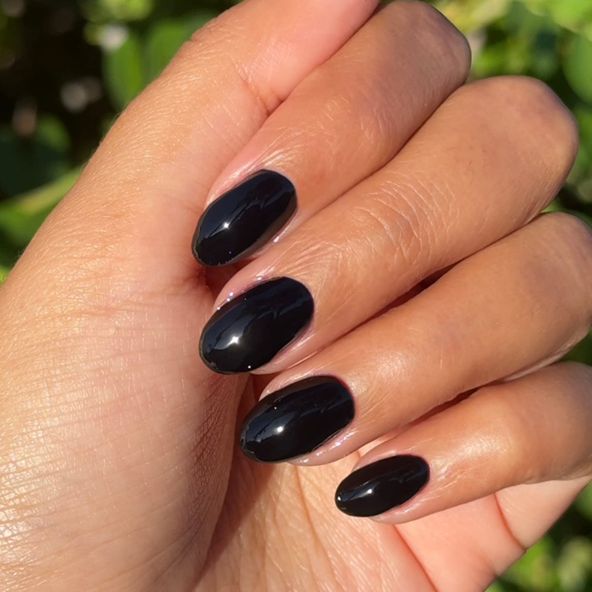E+M - Gel shown on hand with glossy, deeply pigmented black nails for a chic, long-lasting gel polish manicure by Olive and June