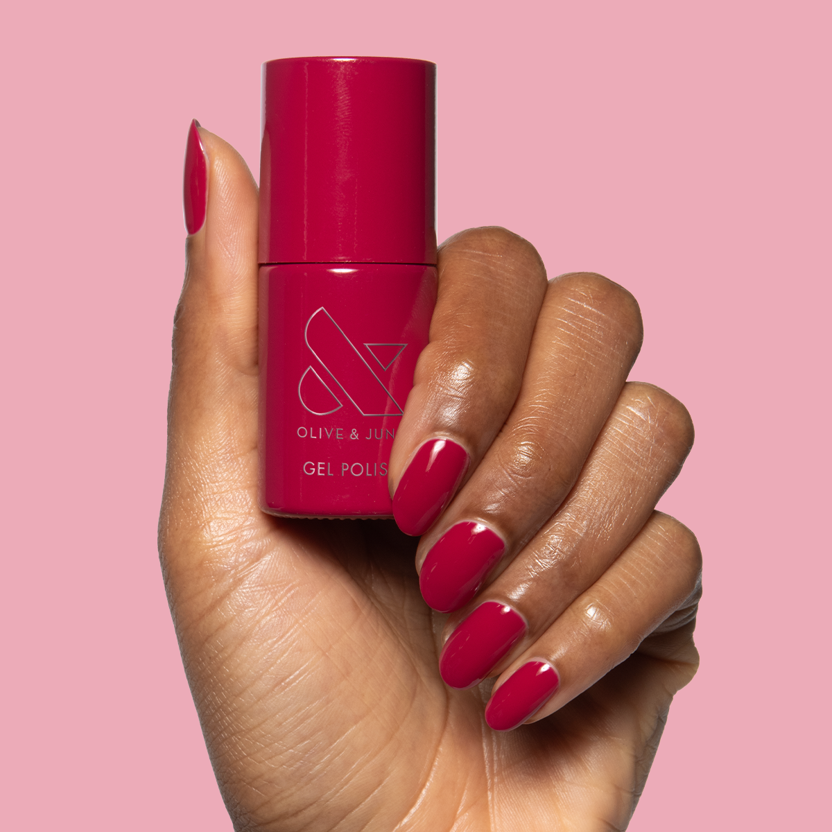 JG - Gel bottle held with matching rich berry gel polish on medium-length nails for a vibrant mani by Olive and June