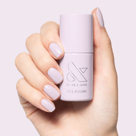 TT - Gel bottle held with matching soft pastel lavender gel polish on neatly manicured nails by Olive and June