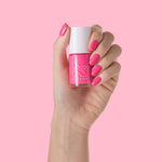 Close-up of a hand holding Hot Strawberry polish with nails painted in bright, nearly neon pink for at-home mani.