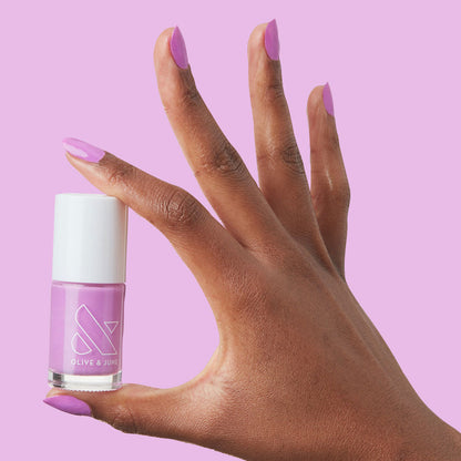 Hand holding Olive and June Jam, Please nail polish with nails painted in glowing soft magenta shade manicure