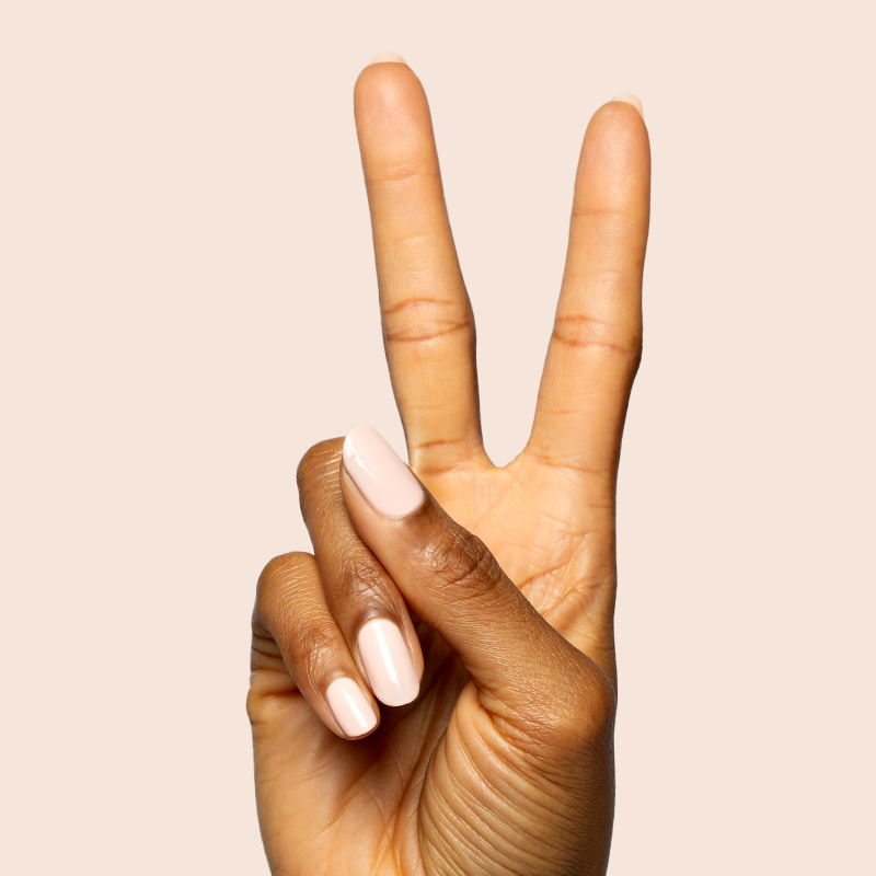 Hand with nails painted in KAG - Gel neutral peachy pink polish making a peace sign on soft beige background