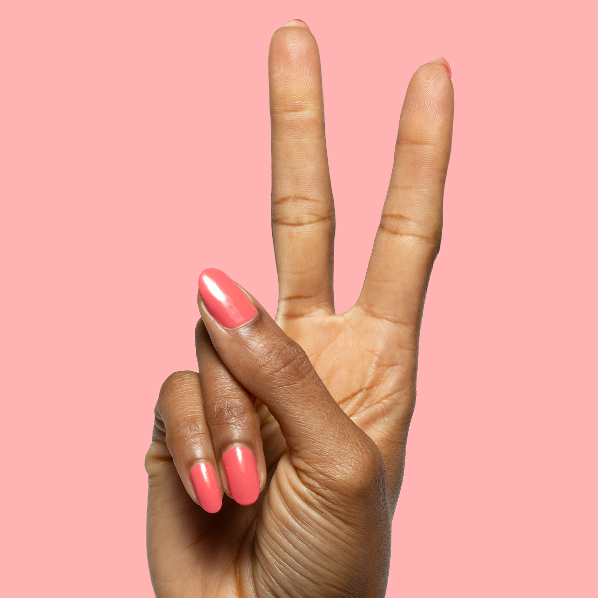 Hand showing peace sign with nails painted in glossy Maine Character Energy gel polish for a vibrant manicure look