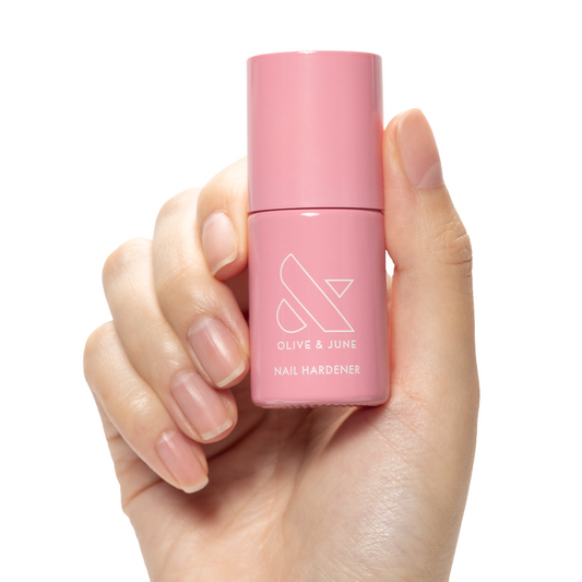 Nail Hardener bottle held by hand with natural nails for strengthening and protection in at-home manicures