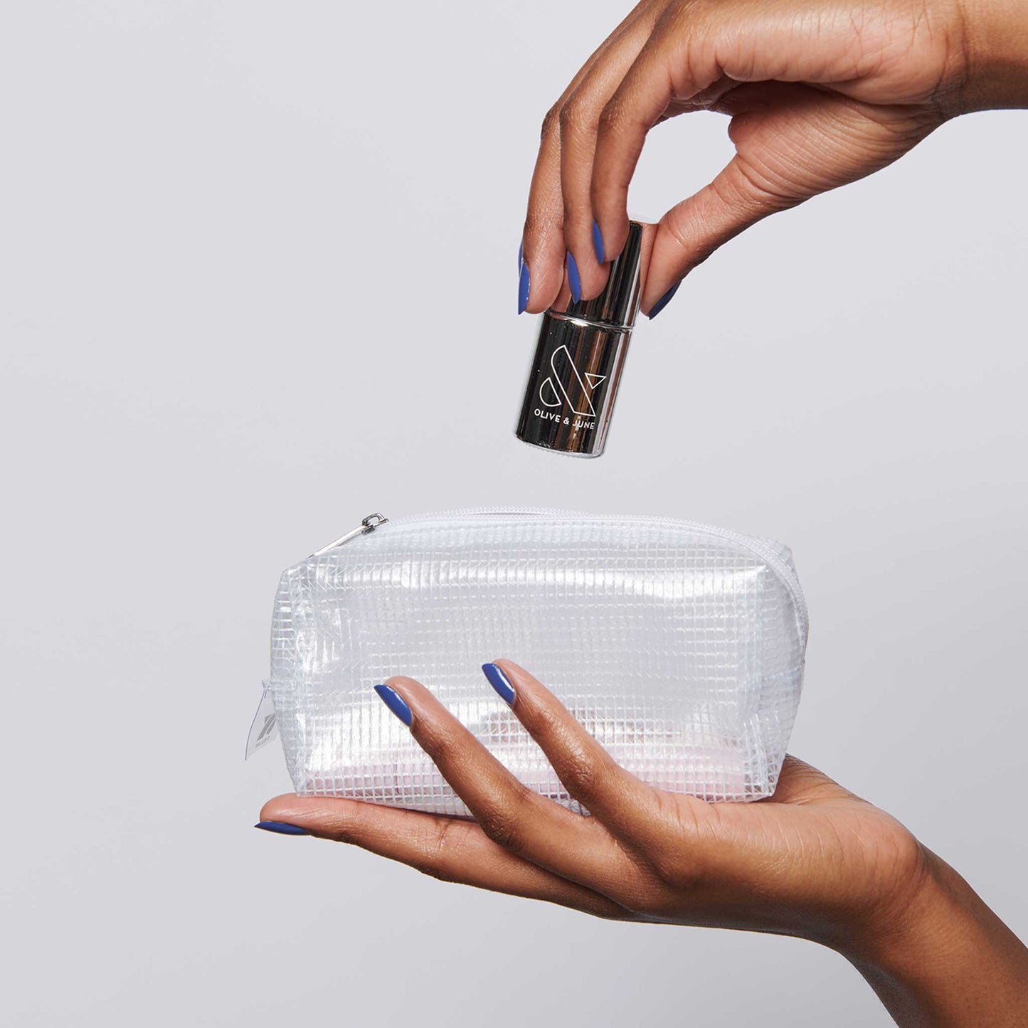 Hands holding The K.I.T. Kit with a clear pouch and nail polish, showcasing essentials for at-home mani care