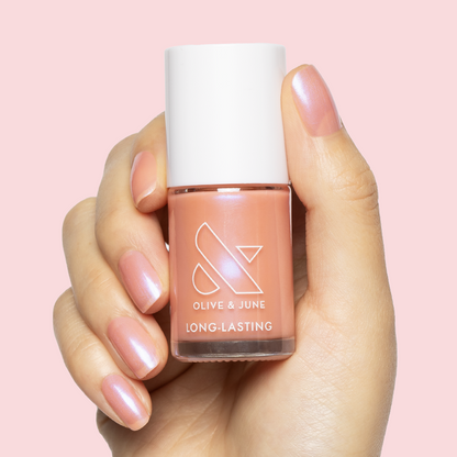 Hand holding Olive and June Olive Y'all nail polish with sheer pink-blue iridescent gel polish manicure