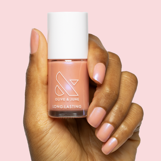 Hand holding Olive and June Olive Y'all polish showcasing sheer pink-blue iridescent manicure on medium nails