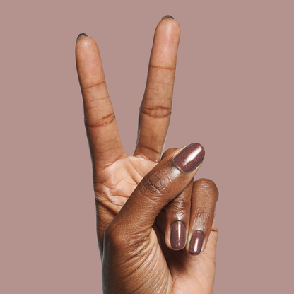 Hand with nails painted in Goal Getter - Gel, a shimmering chocolatey neutral shade, against a muted mauve background