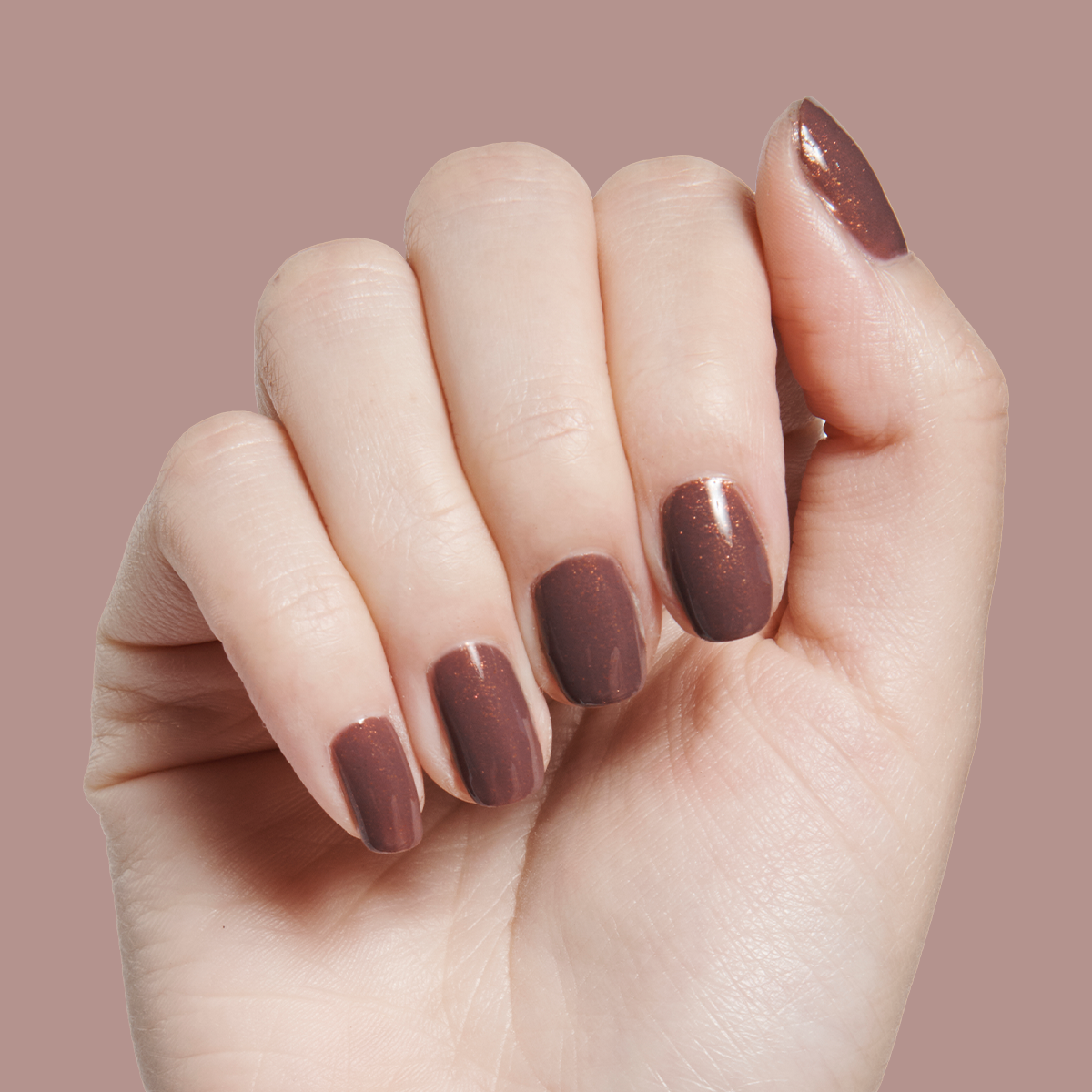 Hand with medium-length nails polished in Goal Getter - Gel, a shimmering chocolatey neutral gel manicure on pale skin