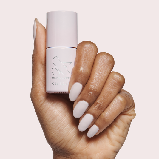 Hand with smooth nails painted in Sculpture Wing - Gel holding matching gel polish bottle on pale background