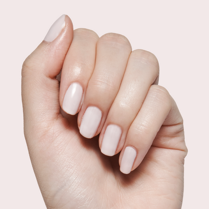 Hand with short nails polished in Sculpture Wing - Gel soft lavender grey gel polish on pale neutral background