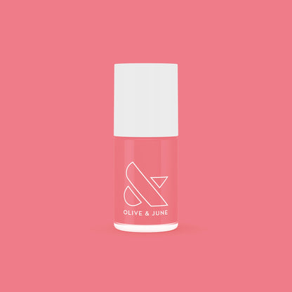 Bottle of Stinson Sunset gel polish by Olive and June in a peachy-pink coral shade on a matching background
