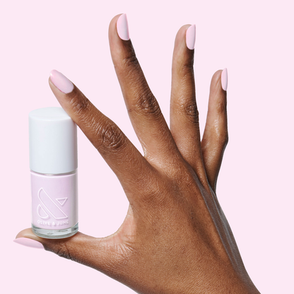 Hand with medium-length nails painted in glossy Cockatoo polish holding a bottle for a smooth at-home manicure