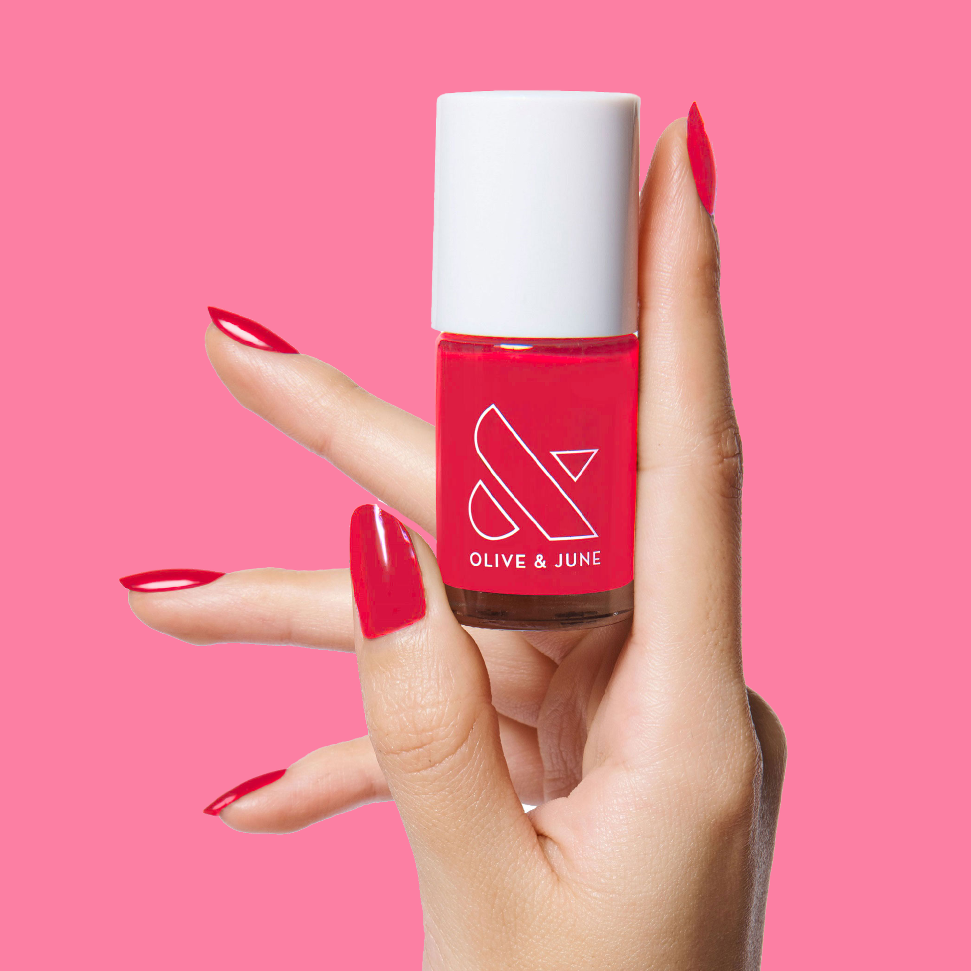 Hand holding a bottle of Hibiscus polish by Olive and June with nails painted in bright tropical pink for a vibrant mani