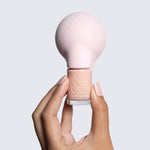 Hand holding The Poppy universal nail polish bottle handle with nude polish for easier at-home manicure control