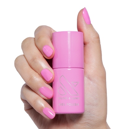 Permanent Vacation - Gel bright pink gel polish bottle held by hand with matching polished nails for mani or pedicure