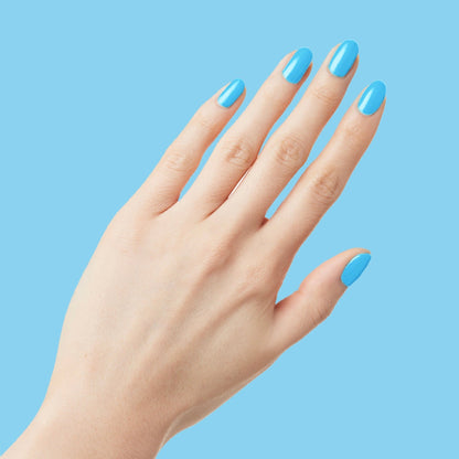 Hand showing neatly manicured nails painted with glossy Megababe Blue gel polish against blue backdrop