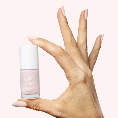 Hand holding Puffball quick dry gel polish bottle with nails painted in sheer milky pink manicure
