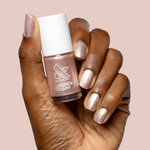 Hand holding Olive and June Supernova polish bottle with nails painted in shimmering sheer pink quick dry manicure color