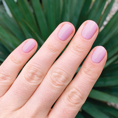 Hand with short nails coated in glossy Cockatoo gel polish by Olive and June for a smooth at-home manicure