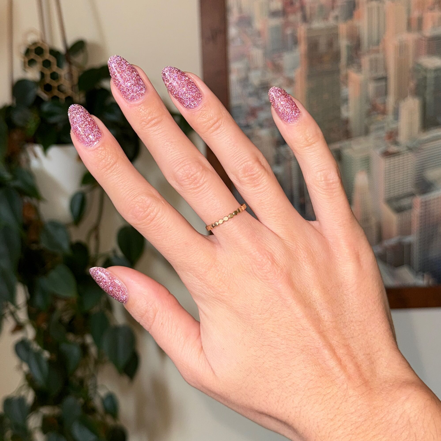 Hand with nails polished in Rosé Rhymes with Partay Gel showing cool-toned pink flash glitter manicure