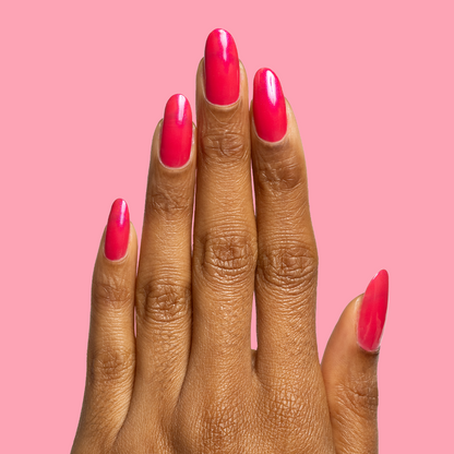 Hand with long nails painted in sheer iridescent berry-pink Berries polish showing smooth gel manicure against pink background