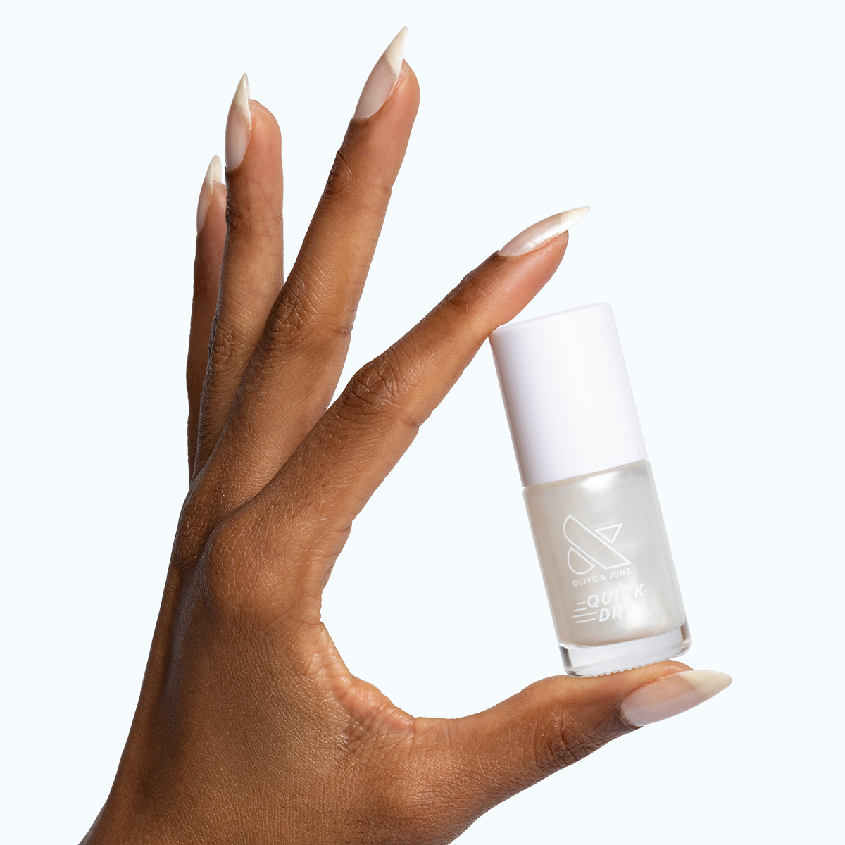 Hand with long almond nails painted in Freshwater sheer pearly white gel polish holding bottle against white background