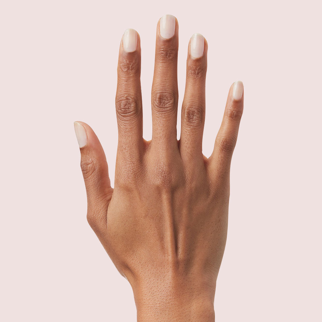 Hand with nails painted in sheer cool pink Strawberry Scone polish for a natural Olive and June manicure