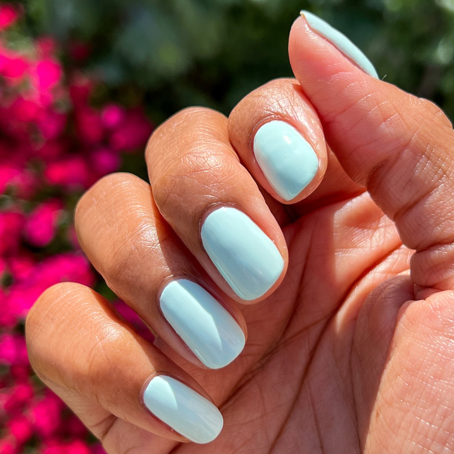 Hand with nails painted in pastel mint green Sleeping Bag gel polish by Olive and June outdoors in natural light